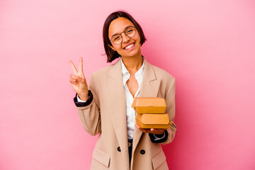 Young business mixed race woman isolated on pink background joyful and carefree showing a peace symbol with fingers.