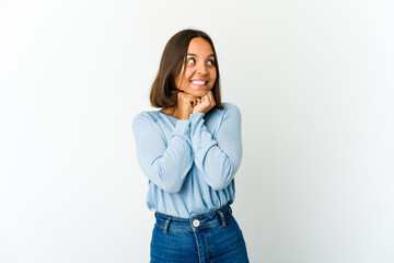 Young mixed race woman keeps hands under chin, is looking happily aside.