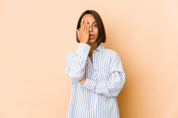 Young hispanic woman isolated having fun covering half of face with palm.