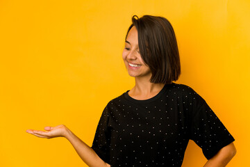 Young hispanic woman isolated on yellow showing a welcome expression.