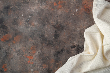 Kitchen table simulating rusty surface with white towel. Top view with copy space. Flat lay.