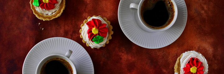 Couple of cups of fresh black strong coffee and sweet cream cake in basket on brown background. Top view, flat lay. Widescreeen panoramic view