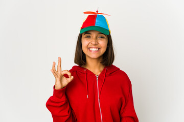 Young hispanic woman wearing a cap with propeller isolated cheerful and confident showing ok gesture.