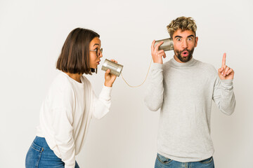 Young hispanic friends talking through a tin can system having some great idea, concept of creativity.