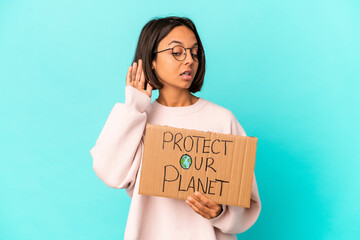 Fototapeta na wymiar Young hispanic mixed race woman holding a protect our planet cardboard trying to listening a gossip.