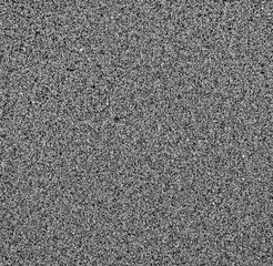 Fine sand grains on a beach, top view of assorted small grains of sand made of various minerals, low contrast black and white image..