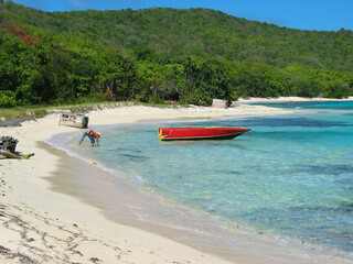 Tropical beach in St Vincent & the Grenadines, white coral sand, blue ocean water and lush green...
