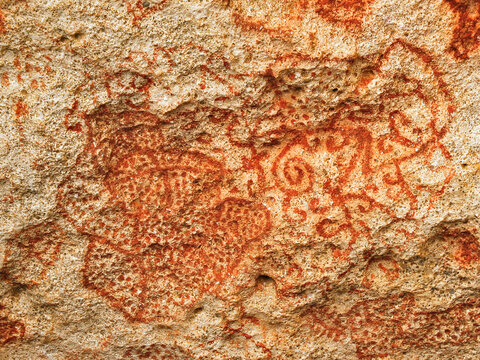 Carib or Arawak cave paintings in red dye on a rock wall, authentic pre-Columbian art in Caribbean Islands.