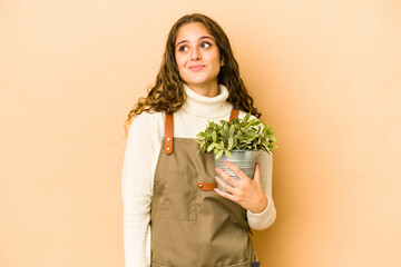 Young caucasian gardener woman holding a plant isolated dreaming of achieving goals and purposes