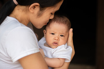 Young Asian mother kissing and holding little daughter in the park, Mother play enjoying with her cute baby girl in outdoor, copy space
