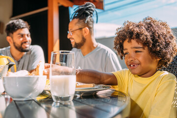 Latinx gay couple having breakfast with their curly-haired son