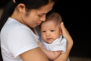 Young Asian mother kissing and holding little daughter in the park, Mother play enjoying with her cute baby girl in outdoor, copy space

