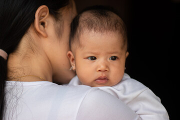 Mother was holding the baby with dark background
