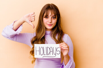 Fototapeta na wymiar Young caucasian woman holding a Holidays placard isolated showing a dislike gesture, thumbs down. Disagreement concept.