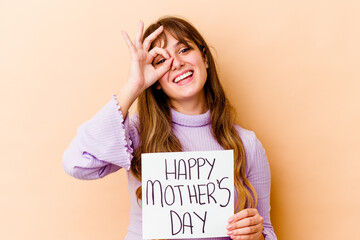 Fototapeta na wymiar Young caucasian woman holding a Happy mothers day placard isolated excited keeping ok gesture on eye.