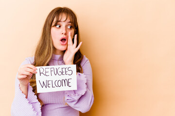 Young caucasian woman holding a Refugees welcome placard isolated is saying a secret hot braking...