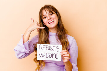 Young caucasian woman holding a Refugees welcome placard isolated showing a mobile phone call...