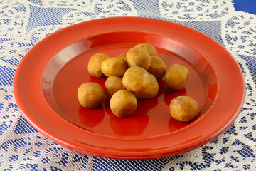 Cocoa dusted marzipan balls on red plate on lace table runner on blue tablecloth