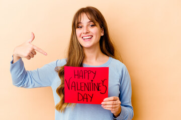 Fototapeta na wymiar Young caucasian woman holding a Happy Valentines day isolated person pointing by hand to a shirt copy space, proud and confident