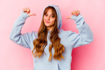 Young caucasian woman with hood isolated on yellow background feels proud and self confident,...