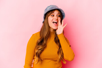 Young caucasian woman wearing fishermans hat isolated shouting and holding palm near opened mouth.