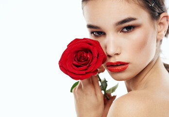 Female portrait with red flower on light background cropped view of naked shoulders