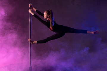 Slim teen pole dancer performing aerial splits