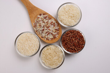 Long grain basmati medium grain jasmine short grain pilaf polau risotto brown low glycaemic index gi rice in small glass bowl wooden spoon on white background copy text space top flat lay view