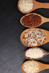 Long grain basmati medium grain jasmine short grain pilaf polau risotto brown low glycaemic index gi rice in wooden spoon on black background copy text space top flat lay view