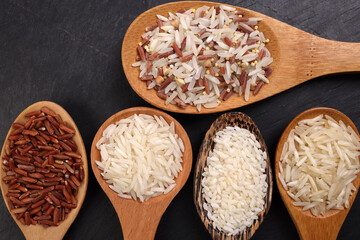 Long grain basmati medium grain jasmine short grain pilaf polau risotto brown low glycaemic index gi rice in wooden spoon on black background copy text space top flat lay view
