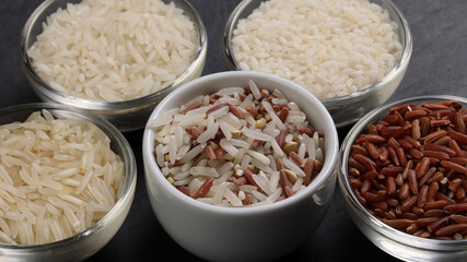 Long grain basmati medium grain jasmine short grain pilaf polau risotto brown low glycaemic index gi rice in small glass bowl on black background copy text space top flat lay view