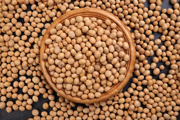 Soyabeans soya beans in wooden bowl flowing over black slate stone background copy text space flat lay top view