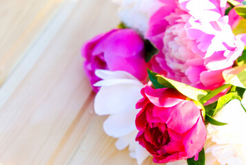 Beautiful colorful peonies on a wooden table, text place.