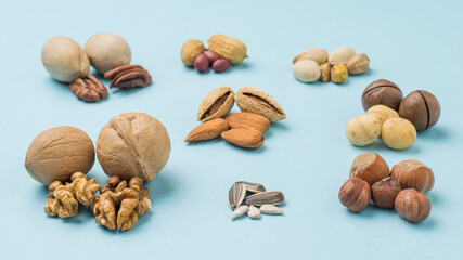 Different types of nuts peeled and unpeeled on a blue background.
