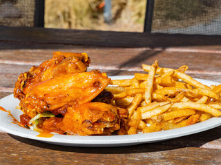 Close up shot of deep fried chicken wings with french fries