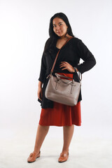 Young woman in casual outfit with stylish bag on white background.