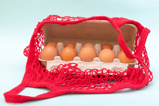 Close-up Of Natural Raw Eggs In A Cardboard Egg Box And In A Red String Bag. Healthy Food Concept