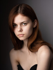 Obraz premium Portrait of a beautiful woman with bare shoulders red hair close-up gray background cropped view