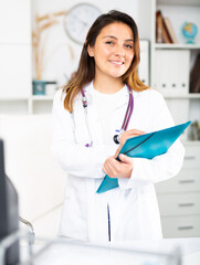 Portrait of friendly female doctor wearing white scrubs uniform and stethoscope