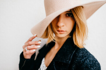 Portrait of elegant stylish blonde short hair girl in hat and jacket posing over white background