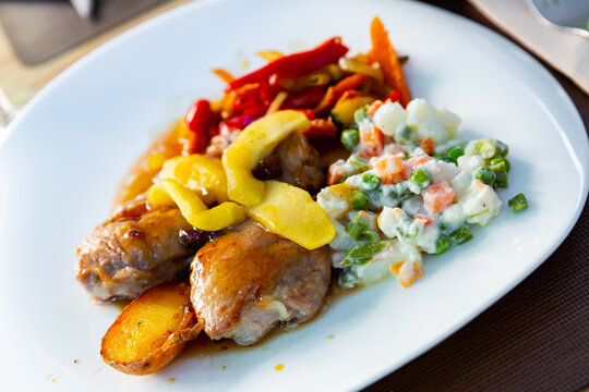 Grilled pork sirloin with caramelized apple, stewed peppers and salad from peas and carrots..