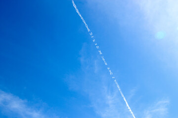 Fototapeta na wymiar White trail left by the airplane in the sky shaped like XOXO