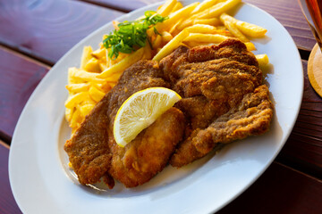 Breaded pork schnitzel with fried potatoes and greens - Czech cuisine