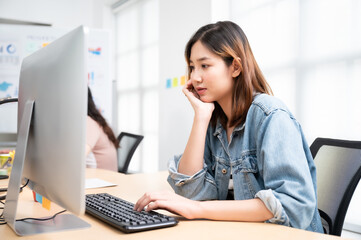 Young asian beautiful woman working on computer at workplace with a business team group