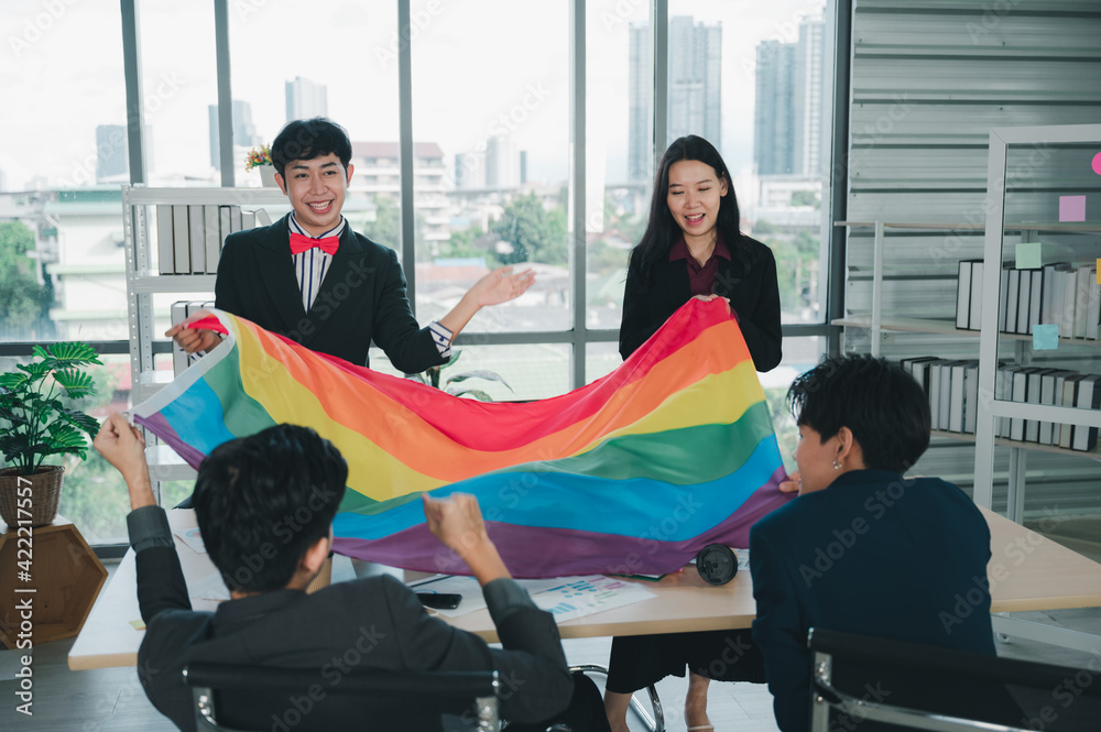 Wall mural Group of LGBTQ businessmen with a rainbow flag in hand are having fun with their colleagues inside the office. The concept of diversity, race and culture, the concept of anti-sexism.