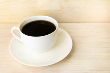 A white coffee cup sits on a wooden surface.