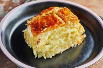 Slice of Potato Pie with Onions, ready after baking on black plate. Step by step recipe