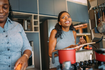 curly haired latinx woman cooking happily at home with her mother