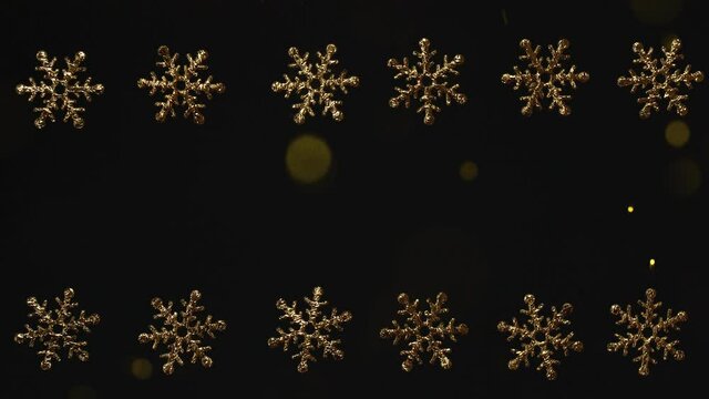 Christmas golden snow flakes border frame on black with flying glitter particles