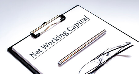 Naklejka premium Paper with Net Working Capital on a table with glasses and pen